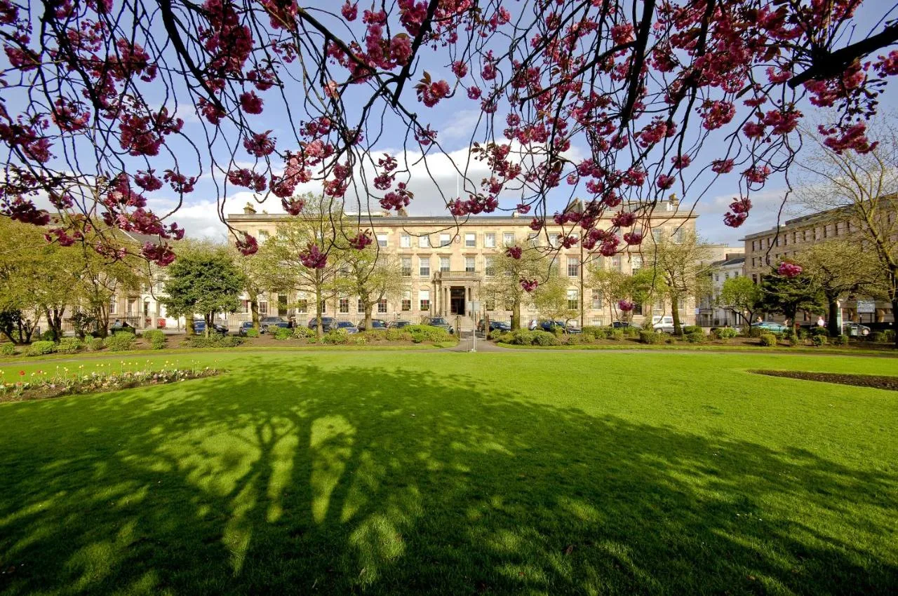 a large building with a green lawn with a tree at Kimpton Blythswood Square Hotel & Spa by IHG in Glasgow